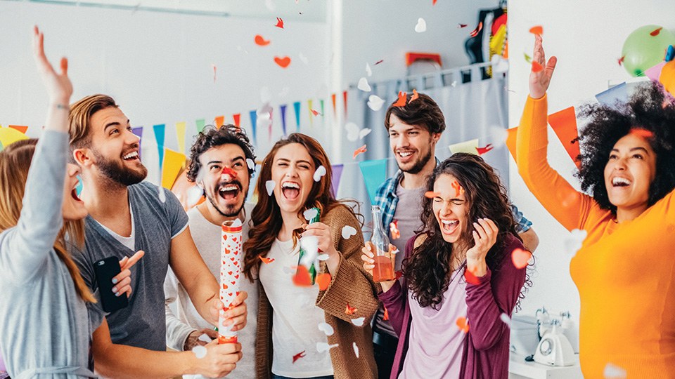 Fröhliche Menschen, die eine Party feiern und gerade eine Konfettikanone gezündet haben.