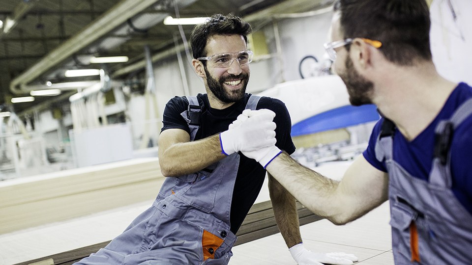 Zwei Arbeiter in Arbeitshosen geben sich die Hand – offensichtlich ein gutes Team.