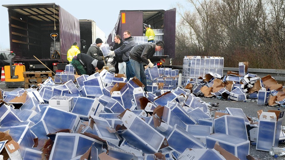 Das Bild zeigt einen stehenden LKW auf der Autobahn mit geöffneter Hintertür. Auf der Fahrbahn liegen etliche Kartons.
