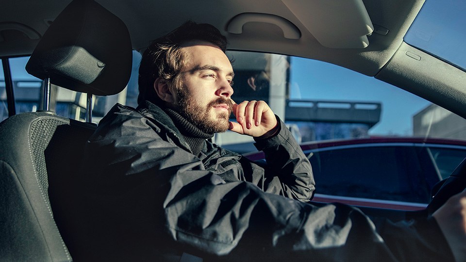 Ein entspannt aussehender Mann sitzt am Steuer seines Autos.