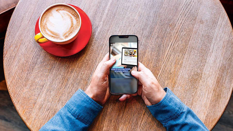 Zwei Hände halten ein Handy, auf dem die Oberfläche des E-Learning-Portals der BG ETEM zu sehen ist.
