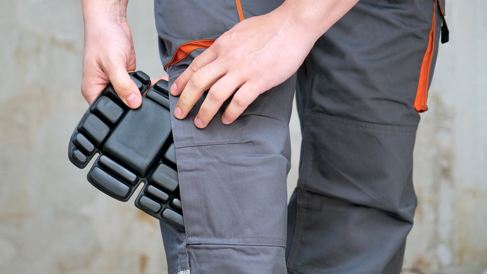 Handwerker schiebt ein Kniepolster in seine Hose
