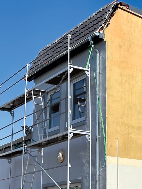 Gefährliche Situation: Ein Gerüst ist mit zwei Gurten an der Dachrinne befestigt